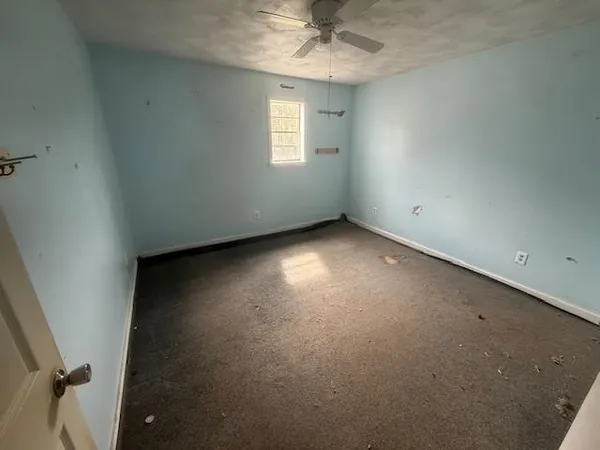 an empty room with a window and a fan