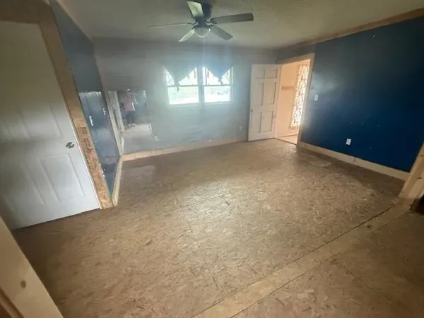 en empty room with windows and ceiling fan