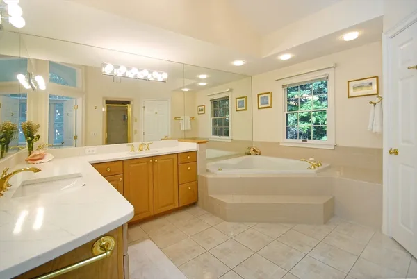 a spacious bathroom with a tub a double vanity sink a mirror and a shower