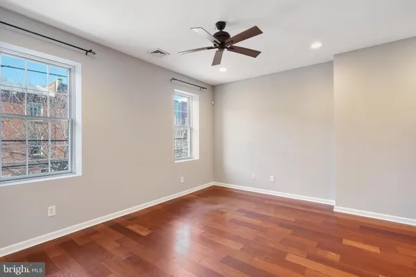 a view of empty room with wooden floor and fan