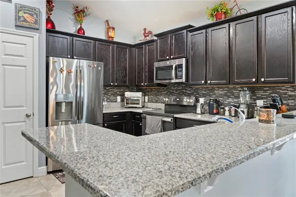 a kitchen with stainless steel appliances granite countertop a refrigerator a stove and a sink with wooden cabinets