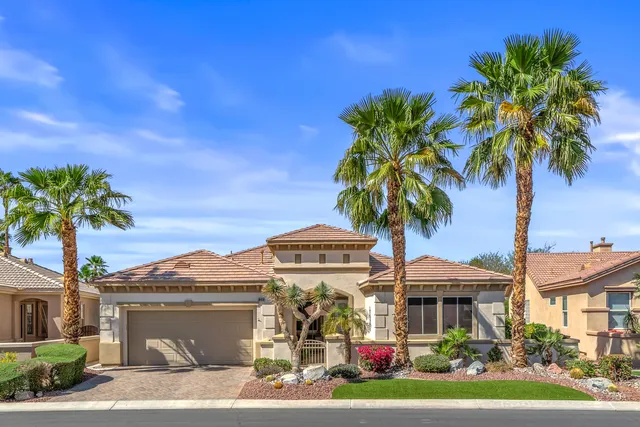 a front view of a house with yard and palm tree