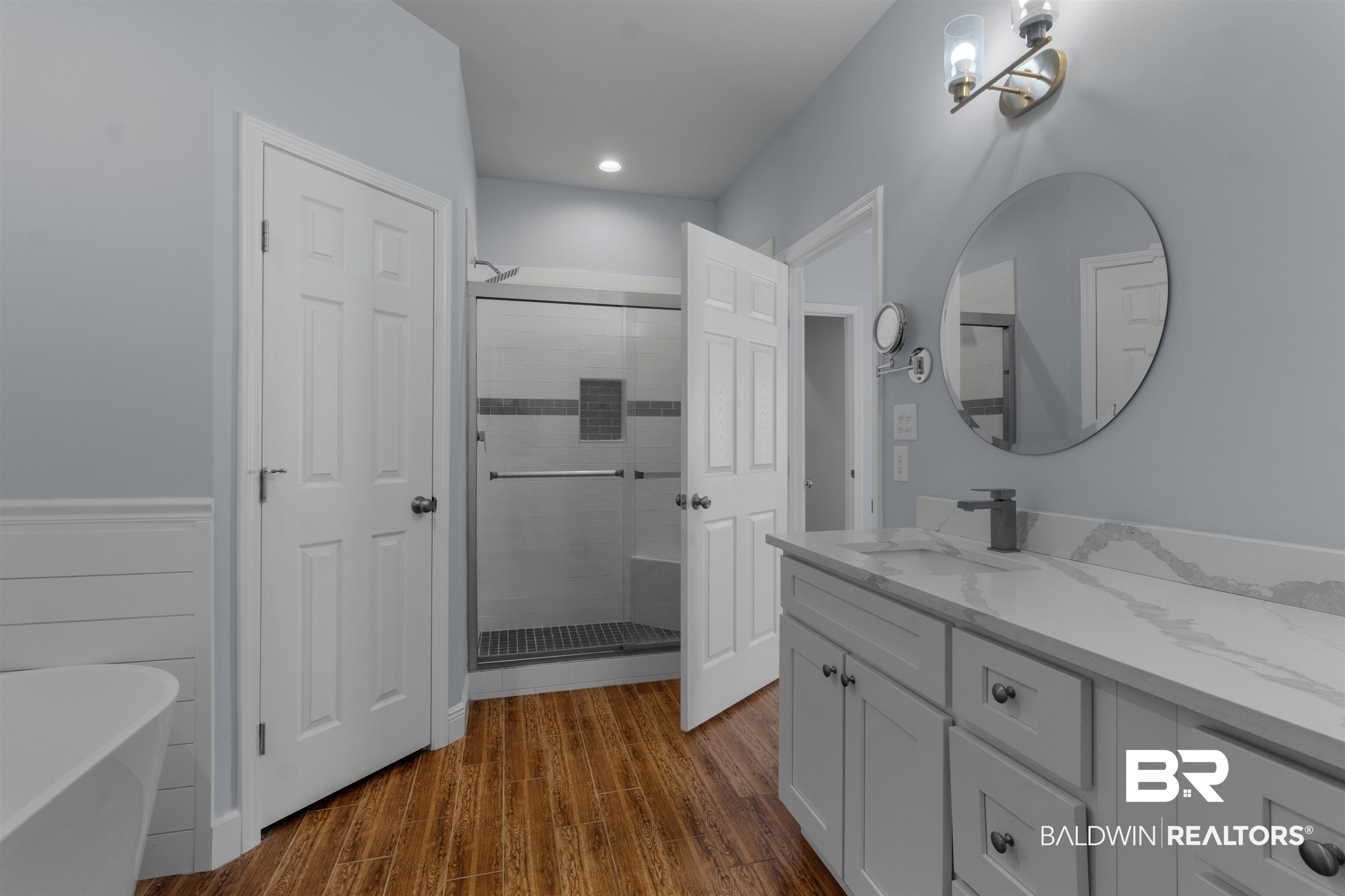 927 Periwinkle Lane Foley, AL 36535 - Photo 9 of 26 Bathroom featuring wood-finish flooring, a freestanding tub, and a shower enclosure with a tile surround