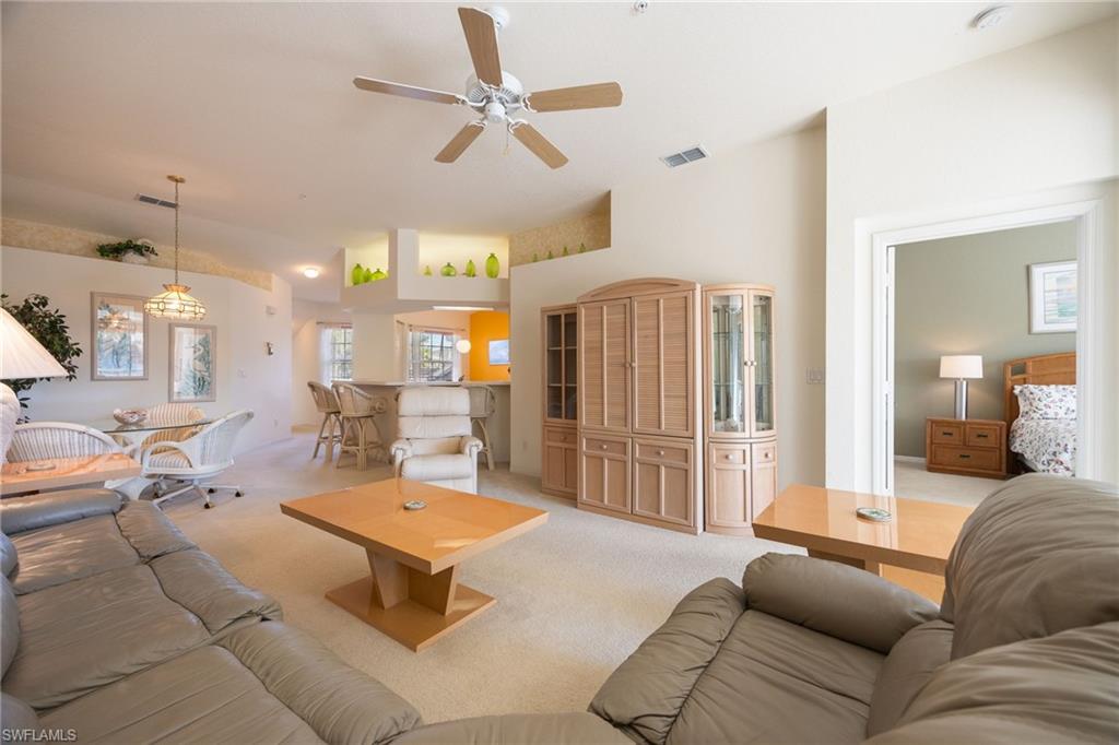 6927 Satinleaf Road North, Unit 203 Naples, FL 34109 - Photo 18 of 39 Living area with light colored carpet, a ceiling fan, and plenty of natural light