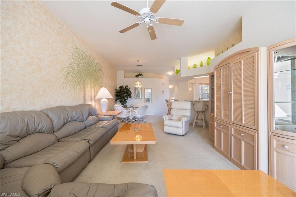 6927 Satinleaf Road North, Unit 203 Naples, FL 34109 - Photo 19 of 39 Living area with wallpapered walls, light colored carpet, and a ceiling fan