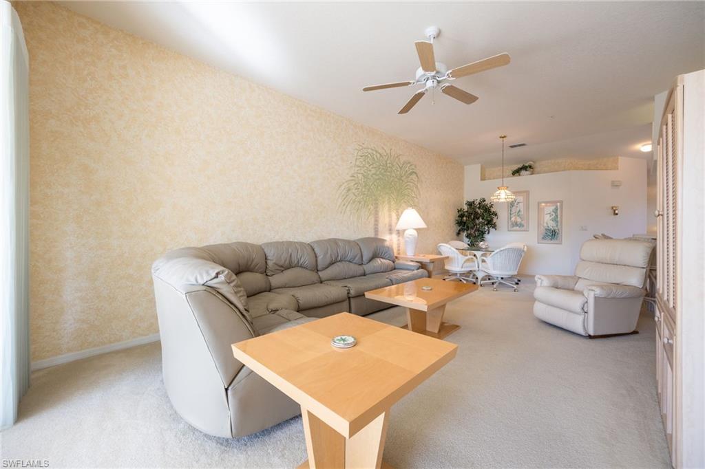 6927 Satinleaf Road North, Unit 203 Naples, FL 34109 - Photo 20 of 39 Carpeted living room featuring a ceiling fan and wallpapered walls