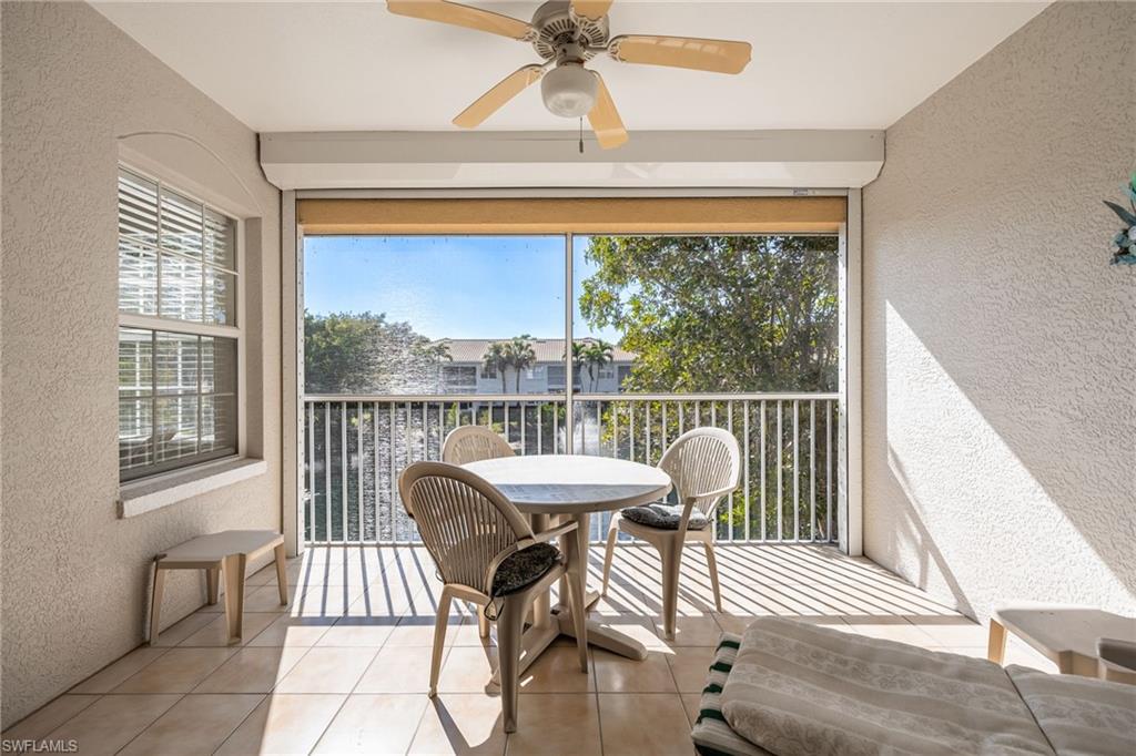 6927 Satinleaf Road North, Unit 203 Naples, FL 34109 - Photo 28 of 39 Sunroom / solarium featuring a textured wall, a balcony, tile patterned flooring, and ceiling fan