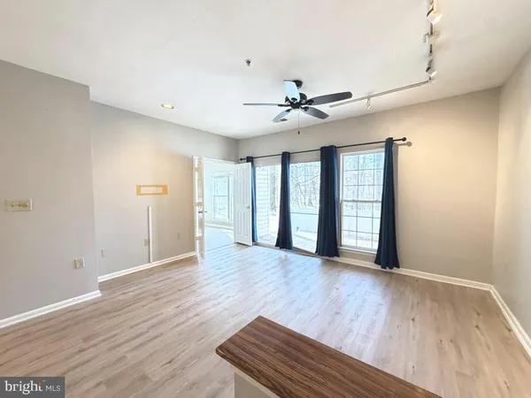 a view of an empty room with window and wooden floor