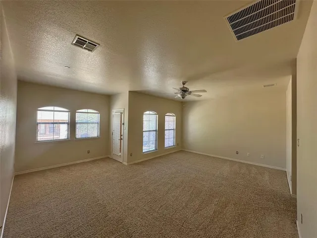 an empty room with windows and ceiling fan