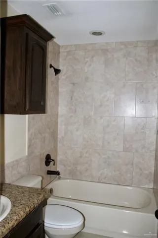 a bathroom with a granite countertop bathtub shower sink and toilet