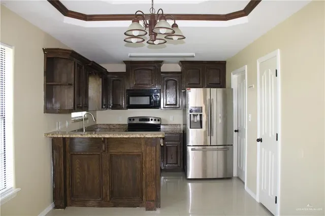 a kitchen with stainless steel appliances granite countertop a refrigerator a stove a sink dishwasher and wooden cabinets with wooden floor