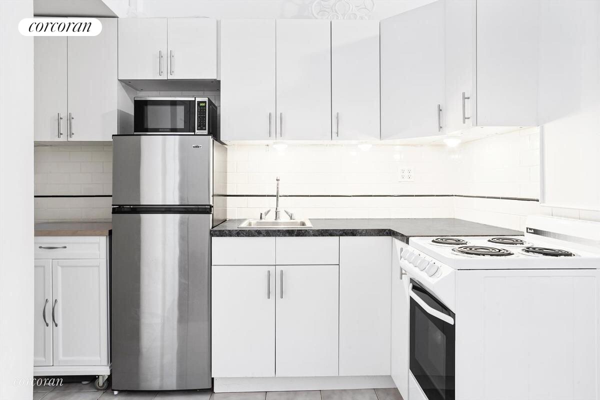 140 West 69th Street, Unit 103B Manhattan, NY 10023 - Photo 2 of 12 a kitchen with stainless steel appliances granite countertop a refrigerator a stove a sink and white cabinets