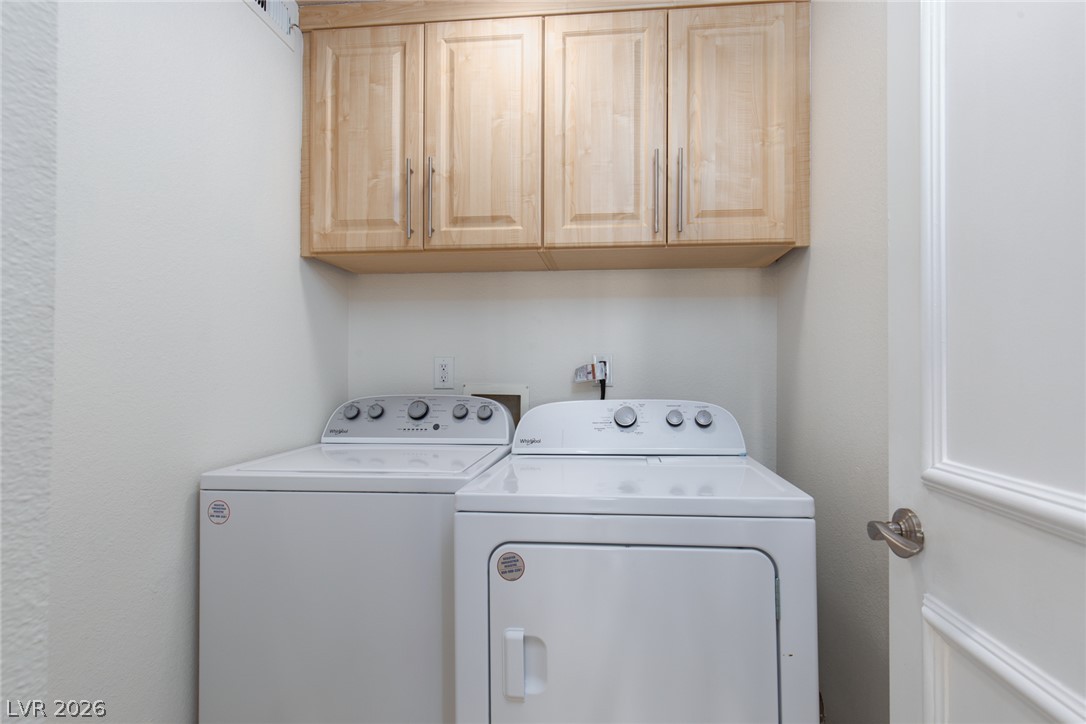 210 East Flamingo Road, Unit 117 Las Vegas, NV 89169 - Photo 12 of 24 A dedicated laundry space features overhead wood cabinetry paired with functional wash and dry units.