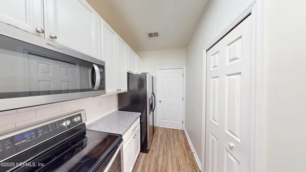 a kitchen with wooden floor electronic appliances and cabinets