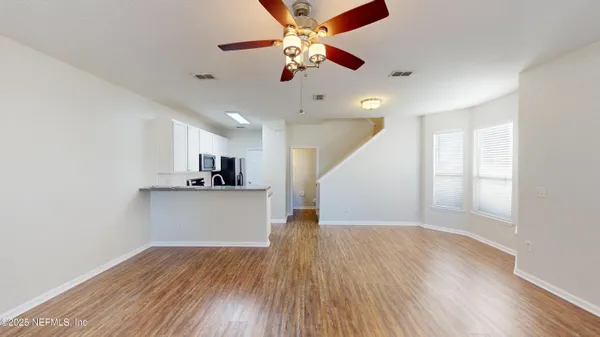 a view of a kitchen with wooden floor and a ceiling fan