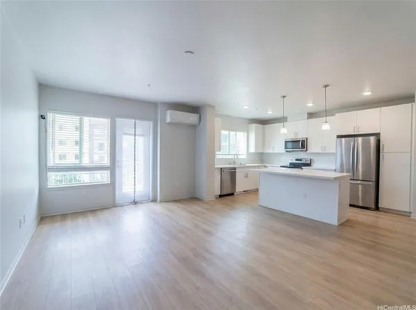 a large kitchen with stainless steel appliances granite countertop a large counter top a wooden floors and a large window