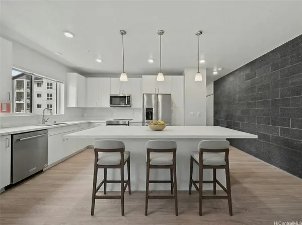 a kitchen with stainless steel appliances granite countertop a sink a stove a refrigerator and white cabinets with wooden floor