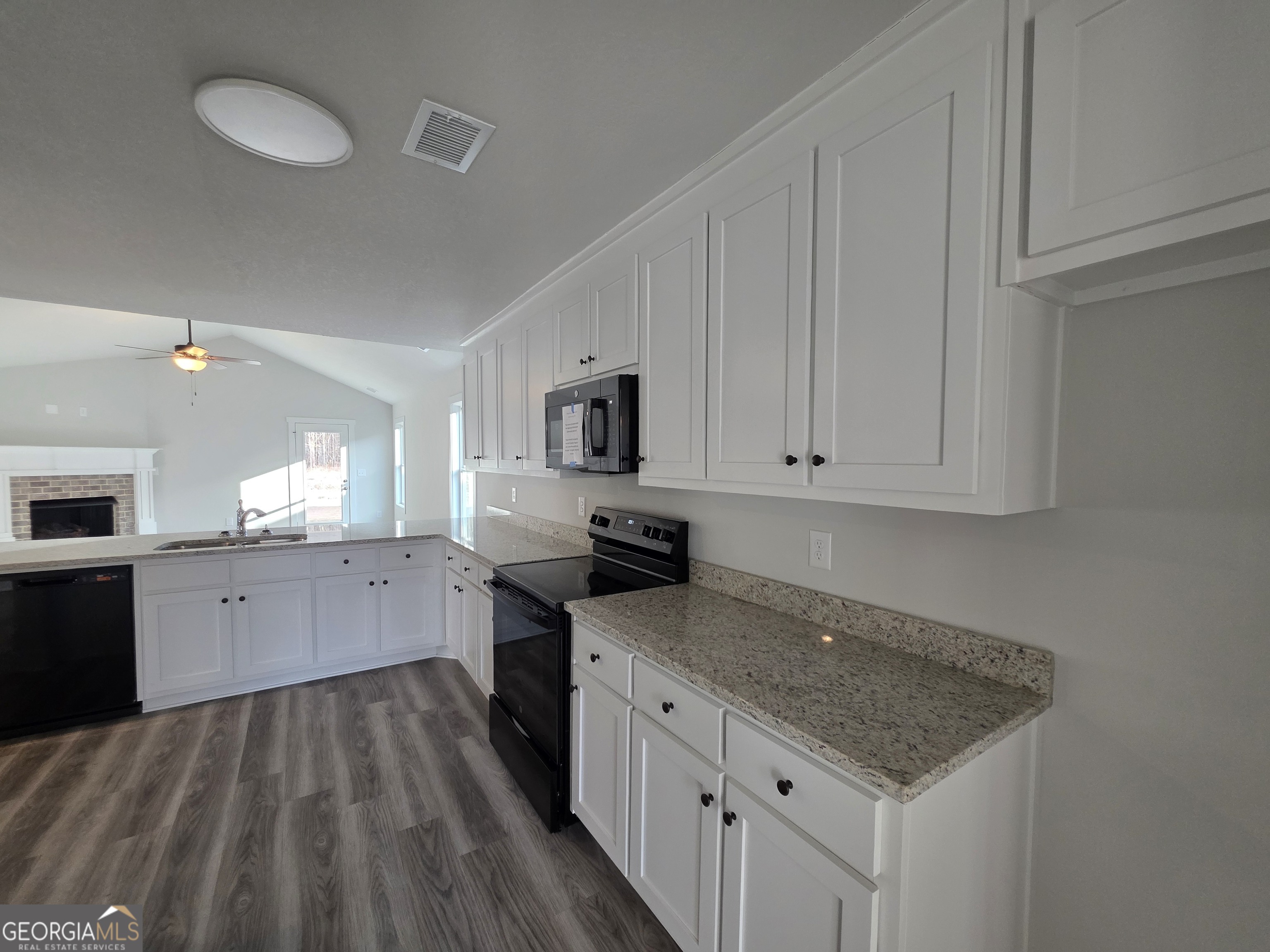 1167 Jeannine Lane, Unit 15 Winder, GA 30680 - Photo 2 of 14 a kitchen with a stove top oven a sink dishwasher and a refrigerator with wooden floor