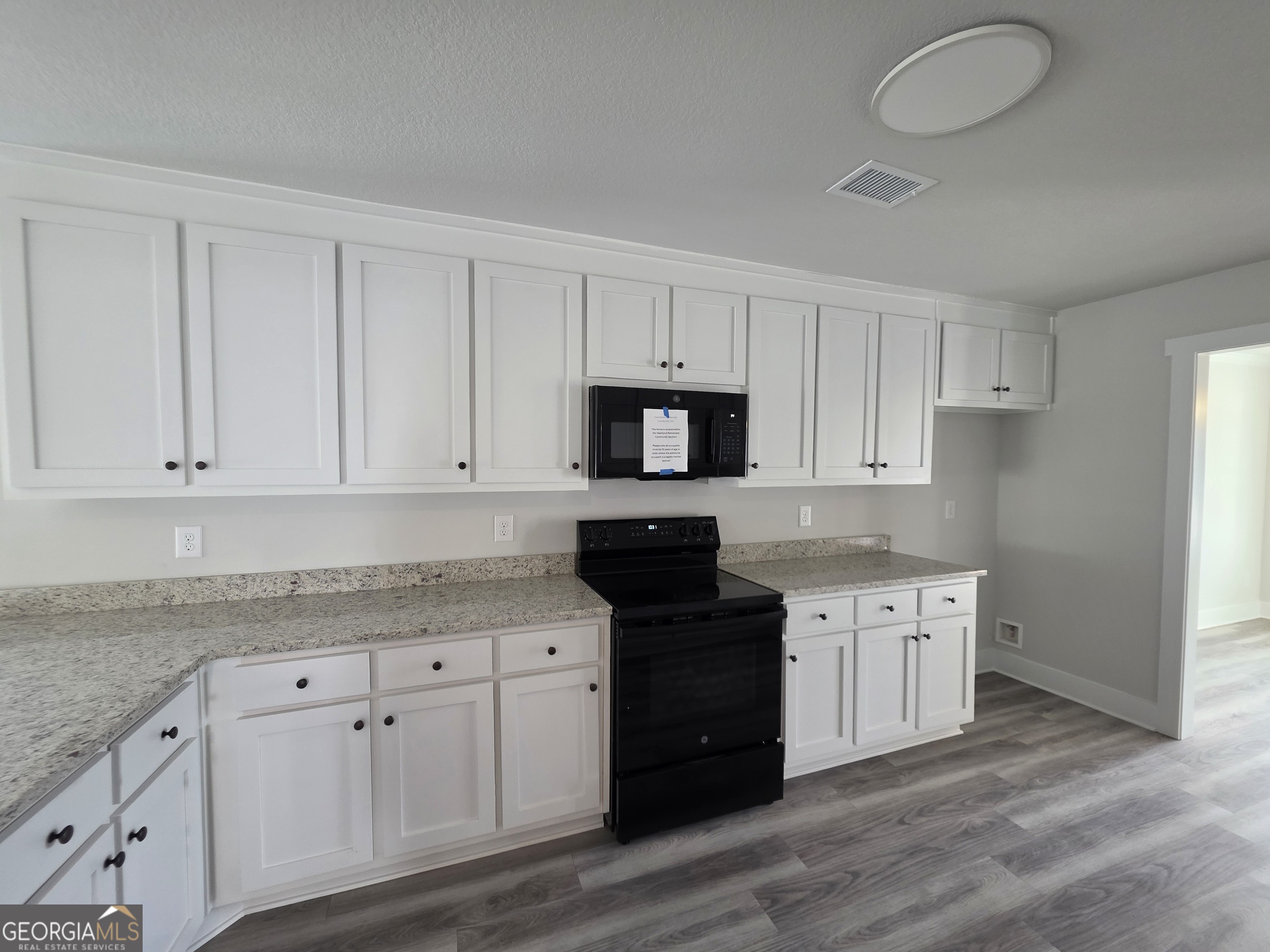 1167 Jeannine Lane, Unit 15 Winder, GA 30680 - Photo 4 of 14 a kitchen with granite countertop white cabinets and stainless steel appliances