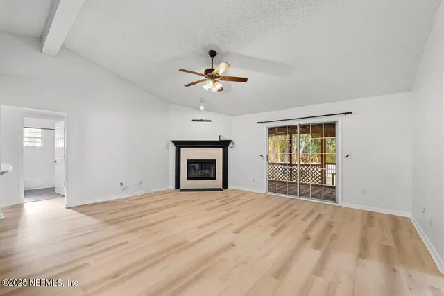 a view of an empty room with a fireplace and a window