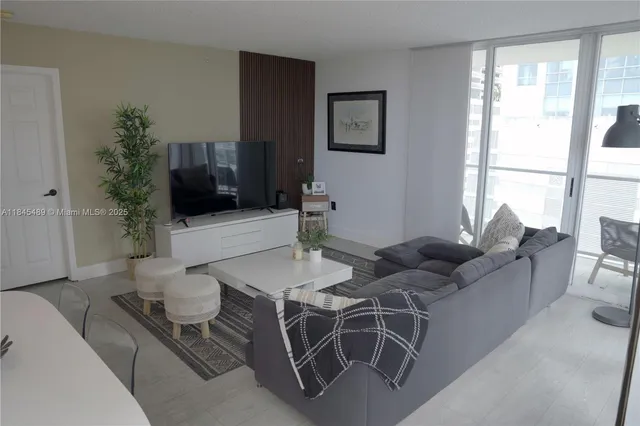 a living room with furniture a flat screen tv and a large window