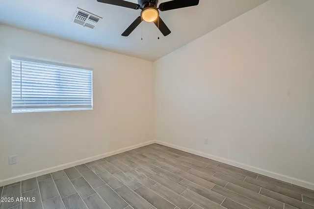 an empty room with wooden floor and a ceiling fan