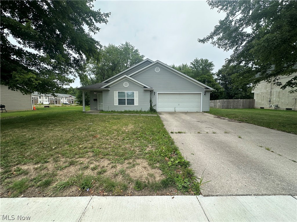 Ranch-style home featuring a garage and a front lawn
