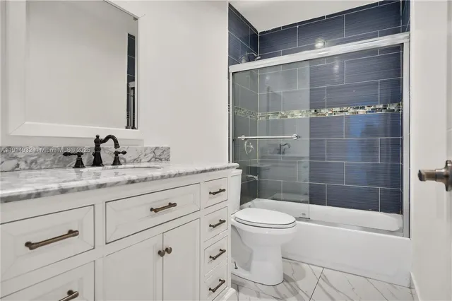 a bathroom with a granite countertop sink a toilet a mirror and shower