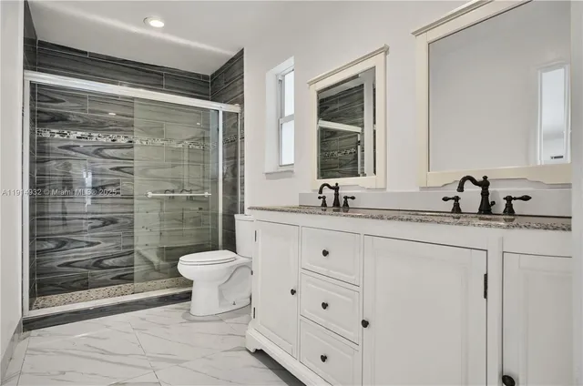 a bathroom with a double vanity sink toilet and shower