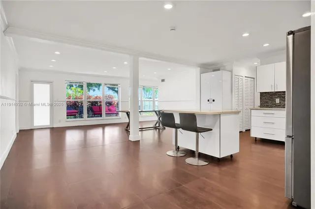 an open kitchen with white cabinets and wooden floor