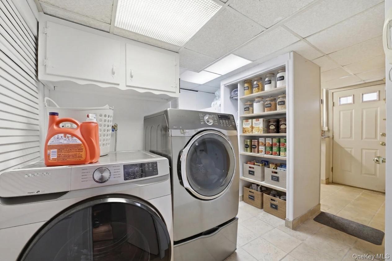 29 Montrose Road Yonkers, NY 10710 - Photo 19 of 39 Dedicated laundry area in basement featuring white upper cabinetry, built-in shelving, and tile flooring