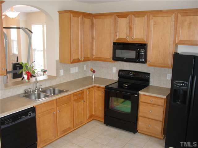 7672 Winners Edge Street Raleigh, NC 27617 - Photo 5 of 17 Large eat in kitchen with beautiful 42 inch kitchen cabinets, nice black appliances and tile floor. Dishes and all appliaces stay with the home!