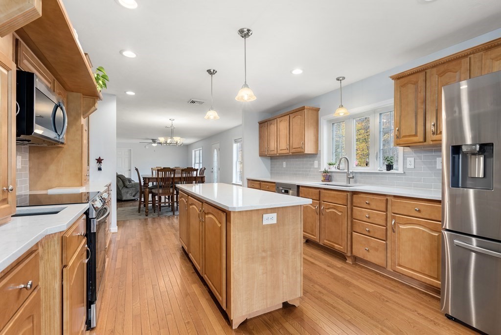 597 Old Warren Road Palmer, MA 01069 - Photo 7 of 37 a kitchen with stainless steel appliances kitchen island granite countertop a stove a sink a refrigerator and a dining table with wooden floor