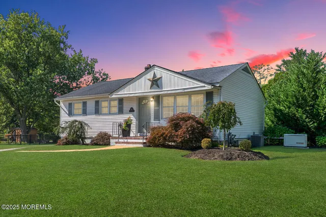 a front view of a house with a yard and tree