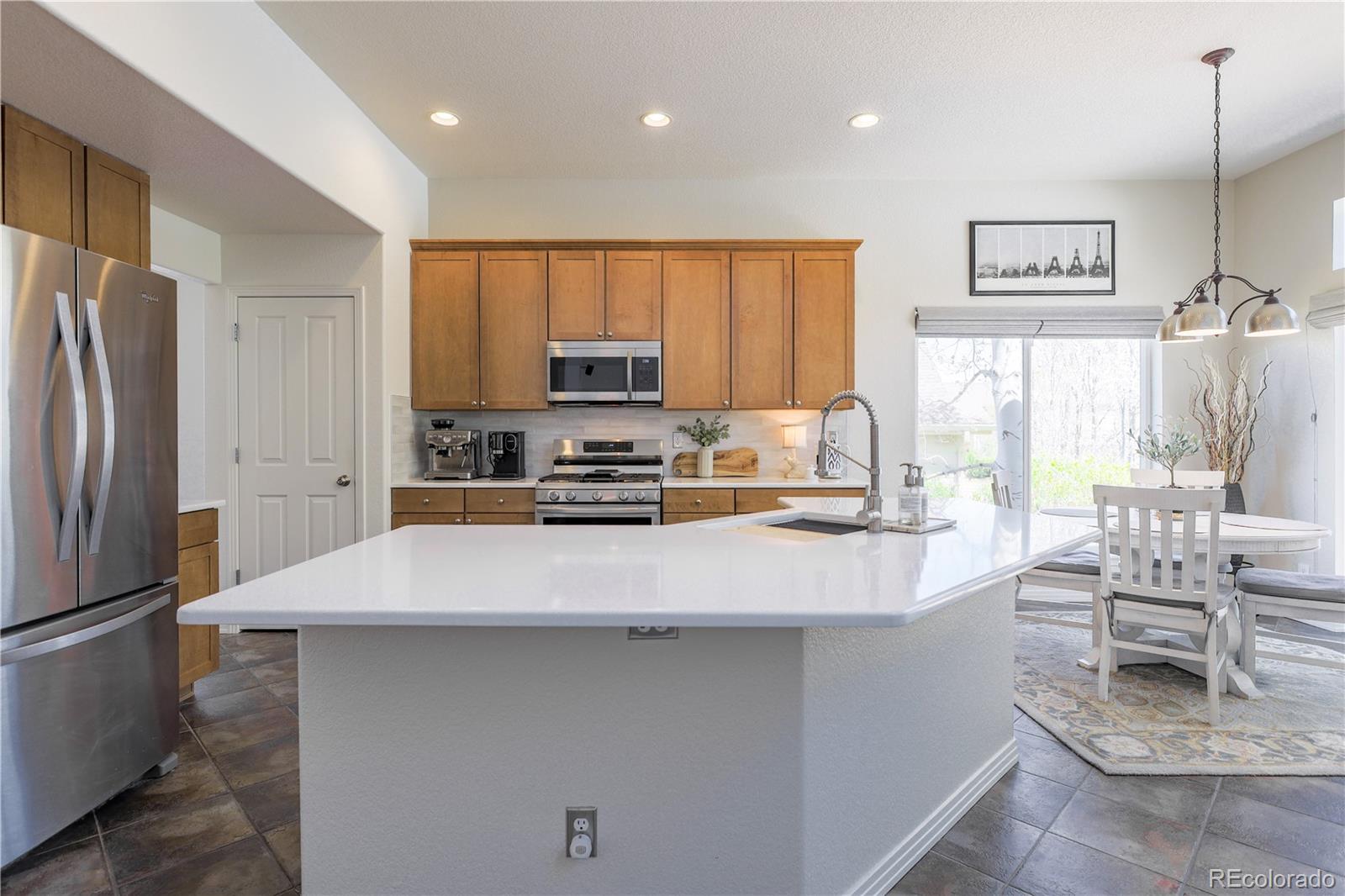 3754 Broadview Place Castle Rock, CO 80109 - Photo 8 of 43 a kitchen with kitchen island a refrigerator a stove a sink a dining table and chairs