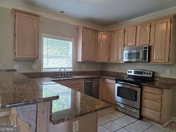 a kitchen with granite countertop a stove sink and microwave