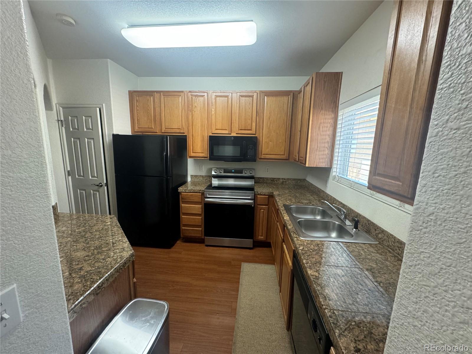 4730 Copeland Circle, Unit 101 Highlands Ranch, CO 80126 - Photo 5 of 14 a kitchen with granite countertop a refrigerator stove and sink