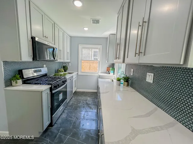 a kitchen with stainless steel appliances granite countertop a stove a sink and a refrigerator