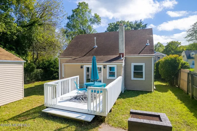 a view of a house with a small yard and a wooden deck