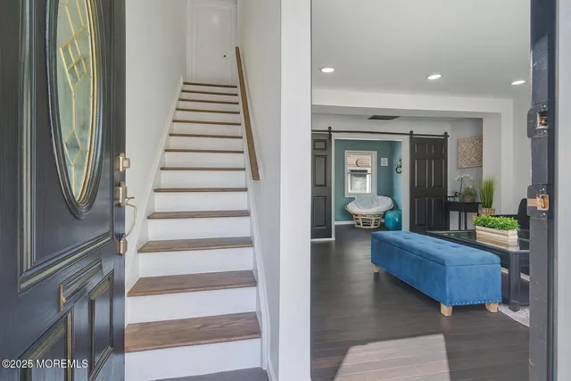 a view of a hallway with couches and potted plant with view of living room