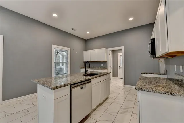 a kitchen with granite countertop a sink and white cabinets
