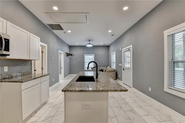 a kitchen with stainless steel appliances granite countertop a sink a stove a counter top space and a window