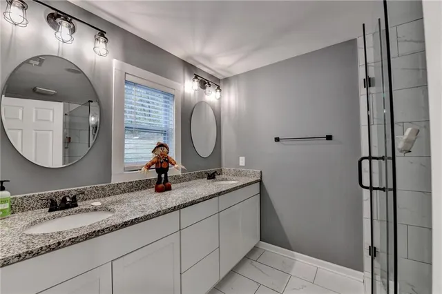 a bathroom with a granite countertop double vanity sink and a mirror