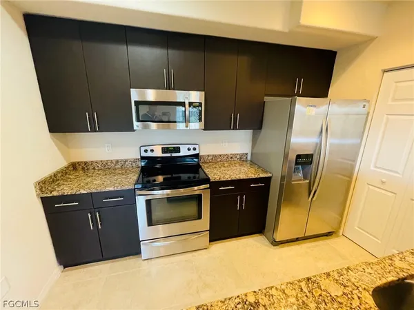 a kitchen with stainless steel appliances granite countertop a stove a refrigerator and a microwave