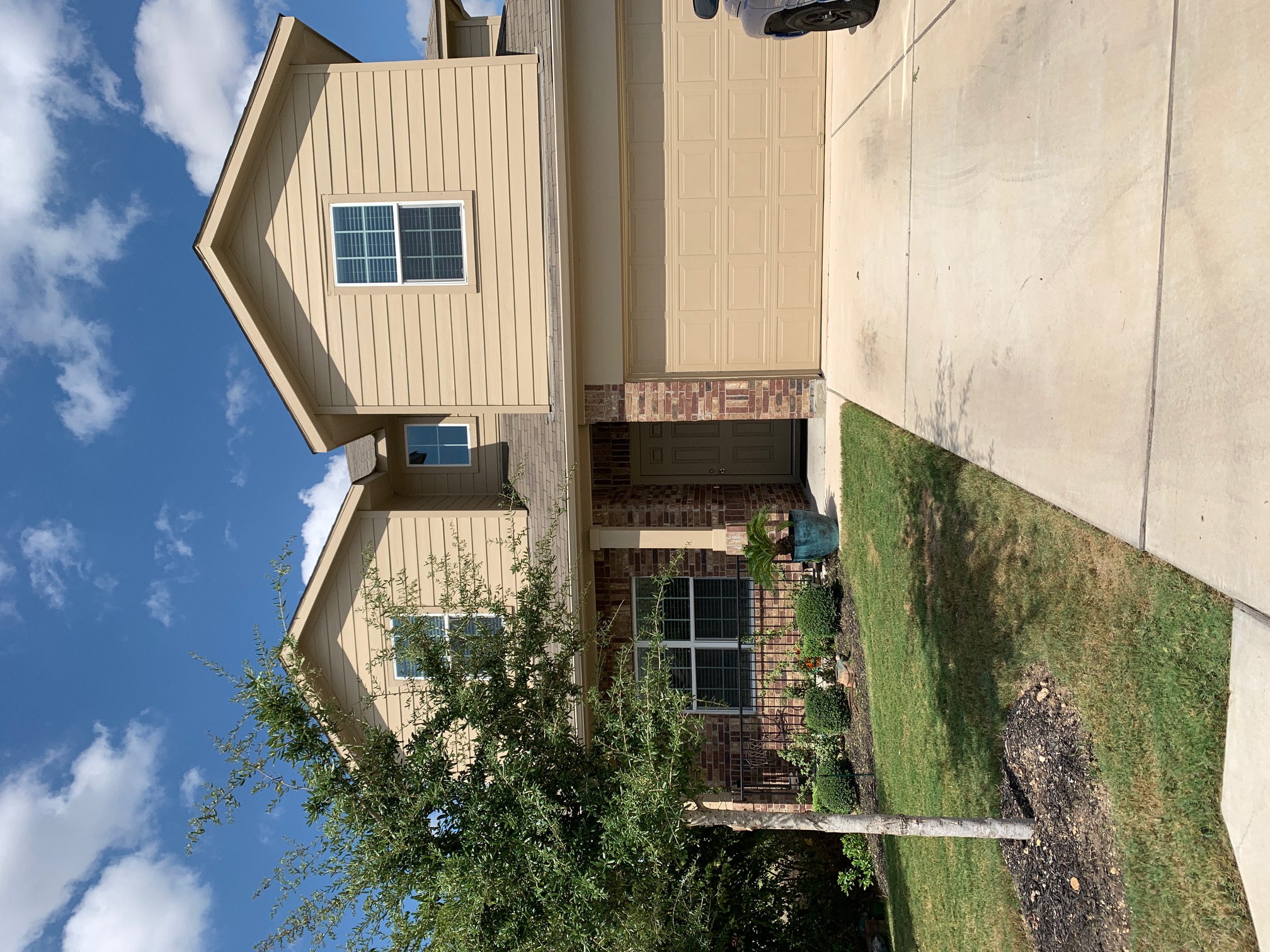 View of front of home featuring a garage, driveway, a front lawn, and brick siding