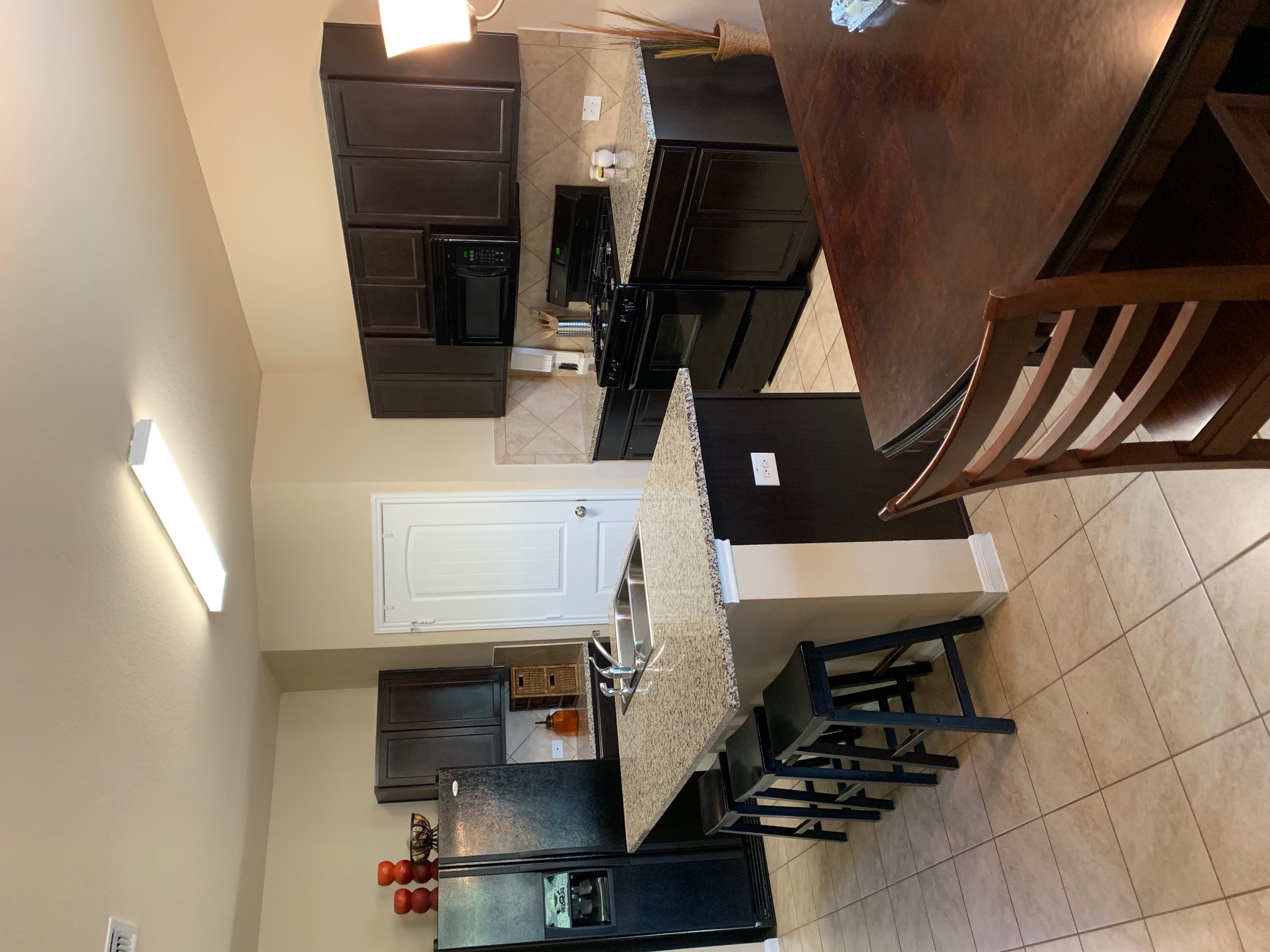 2020 Mottey Street Georgetown, TX 78626 - Photo 6 of 24 Kitchen with black appliances, tasteful backsplash, a kitchen breakfast bar, light tile patterned flooring, and a kitchen island with sink