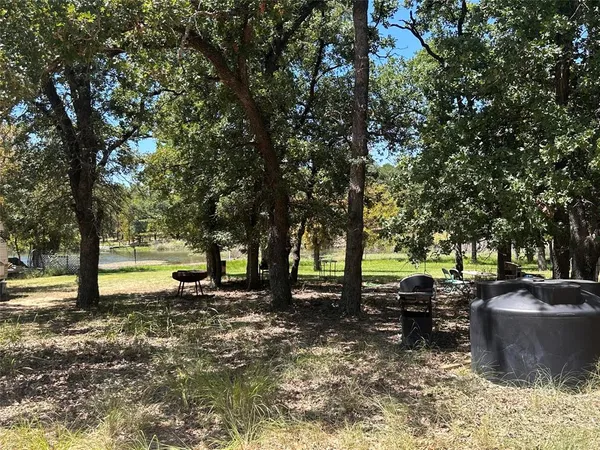 a view of a backyard with table and chairs a fire pit and large trees