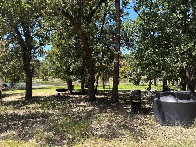 a view of a backyard with table and chairs a fire pit and large trees