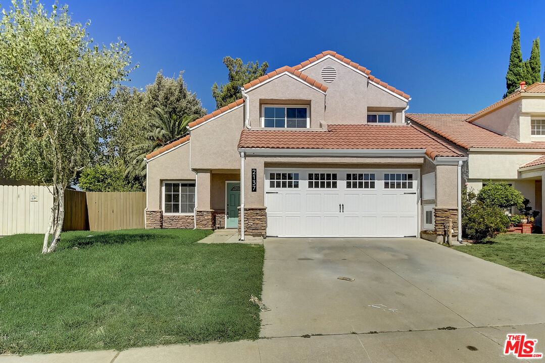 a view of a white house with a big yard and large trees