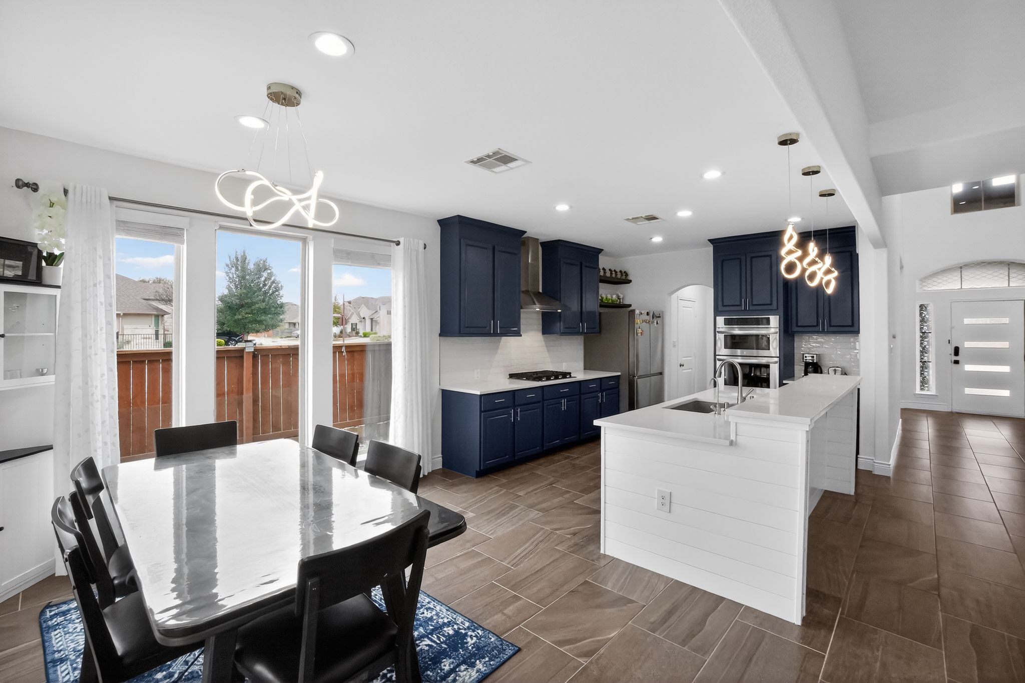 400 Cortona Lane Georgetown, TX 78628 - Photo 15 of 40 Kitchen featuring blue cabinetry, arched walkways, hanging lights, stainless steel appliances, and an island with sink